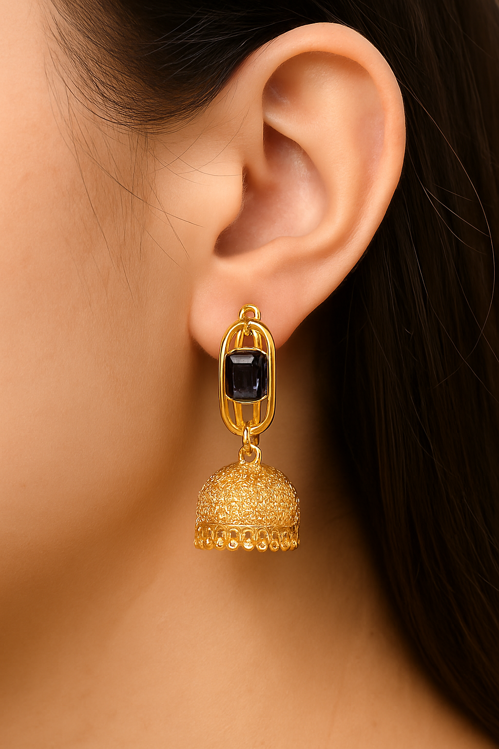 Gold earring with a black gemstone worn by a person