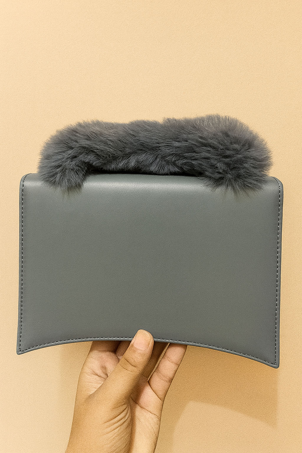 Gray leather wallet with fur trim held against a beige background
