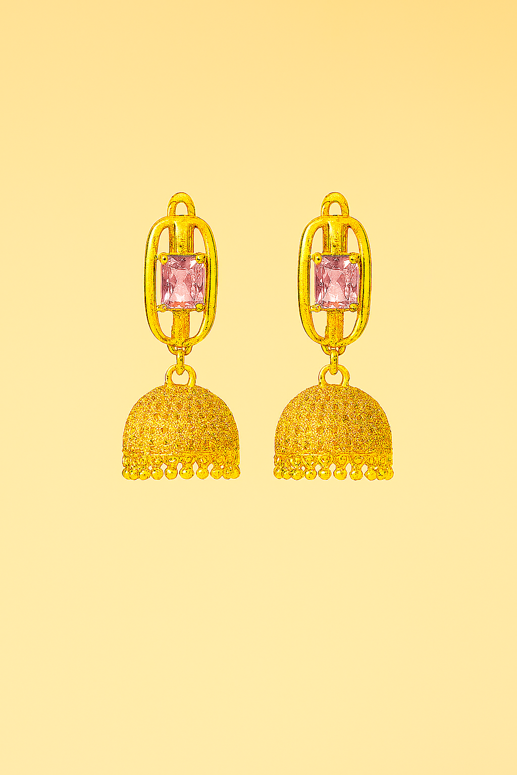 Gold earrings with pink gemstones on a yellow background