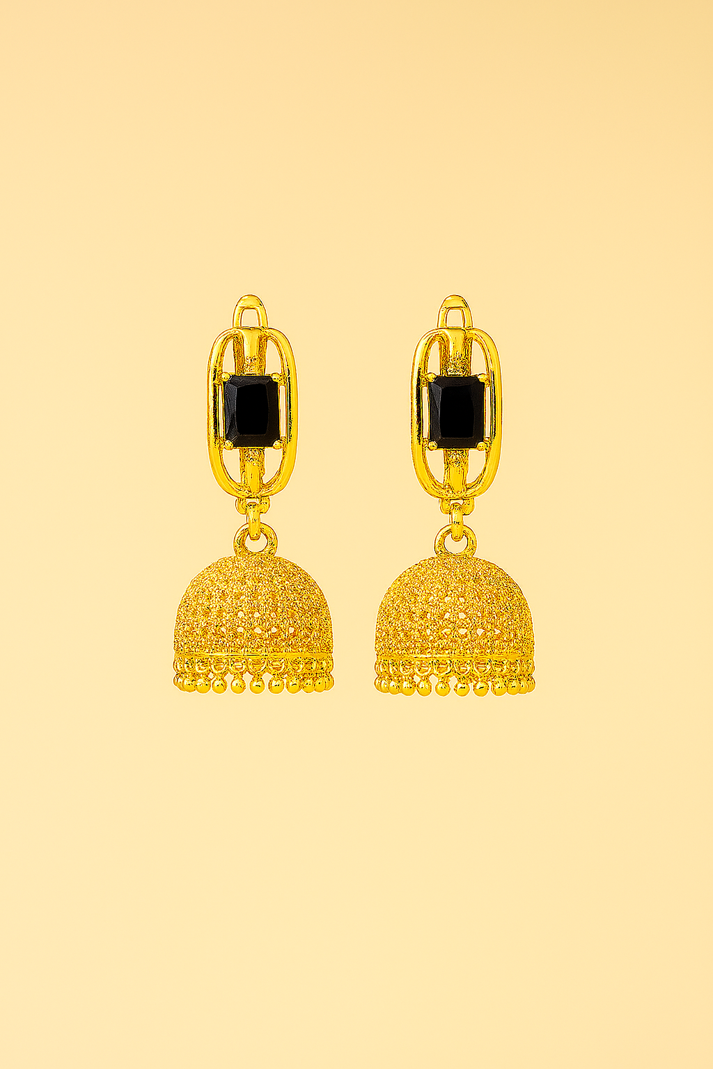 Gold earrings with black stones on a beige background