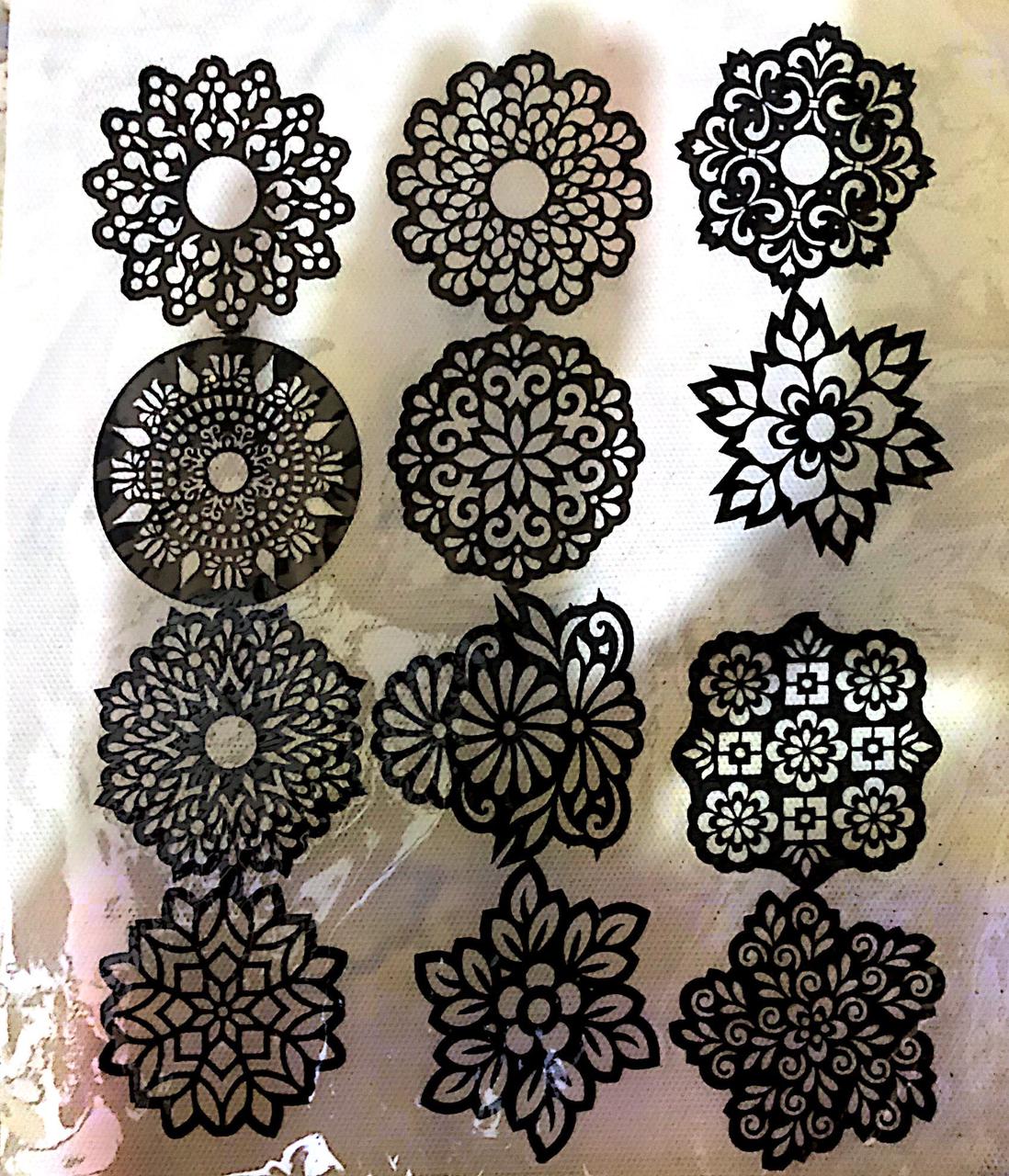 Set of black floral and circular decorative stencils on a textured beige background