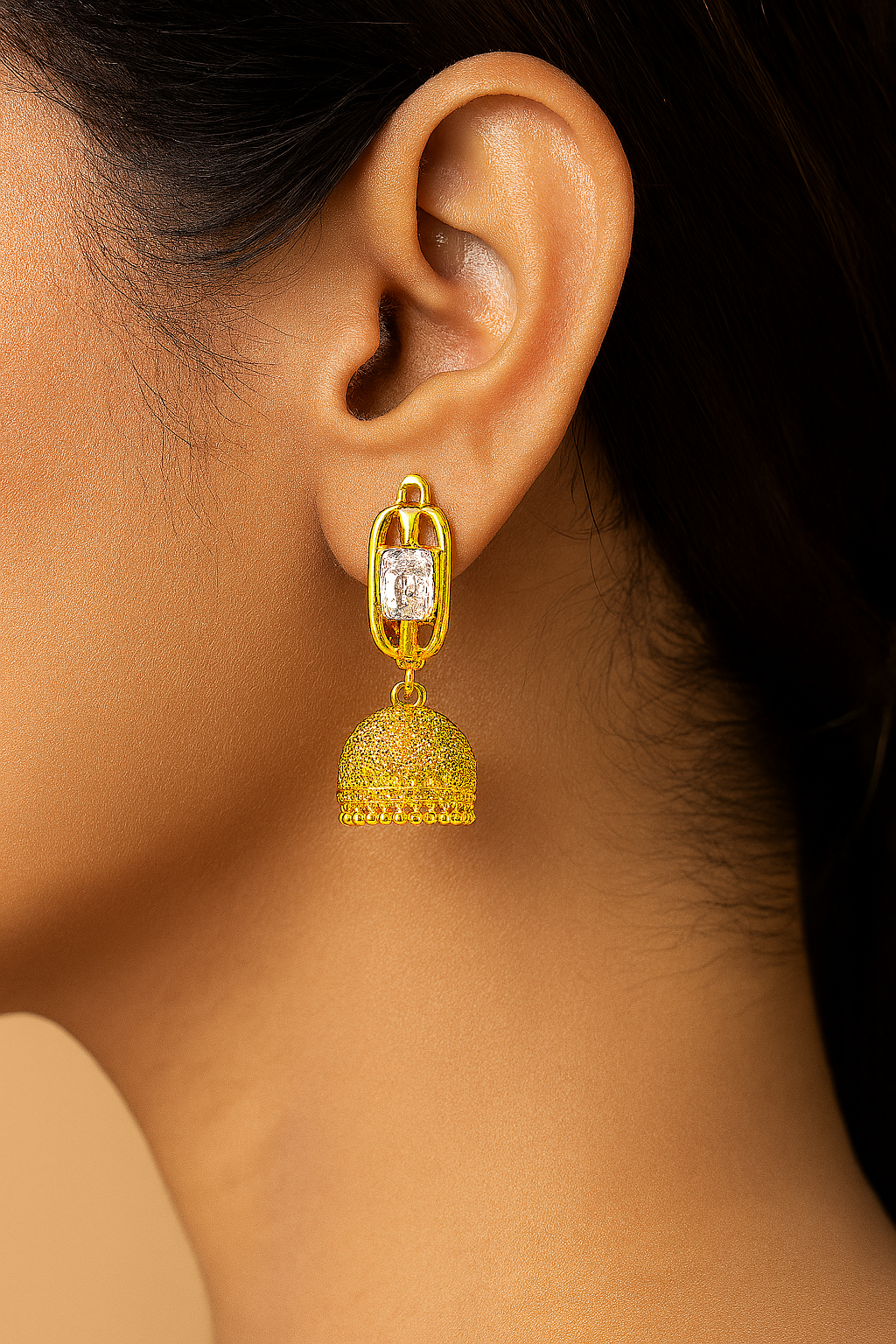 Gold earring with a central gemstone worn by a person