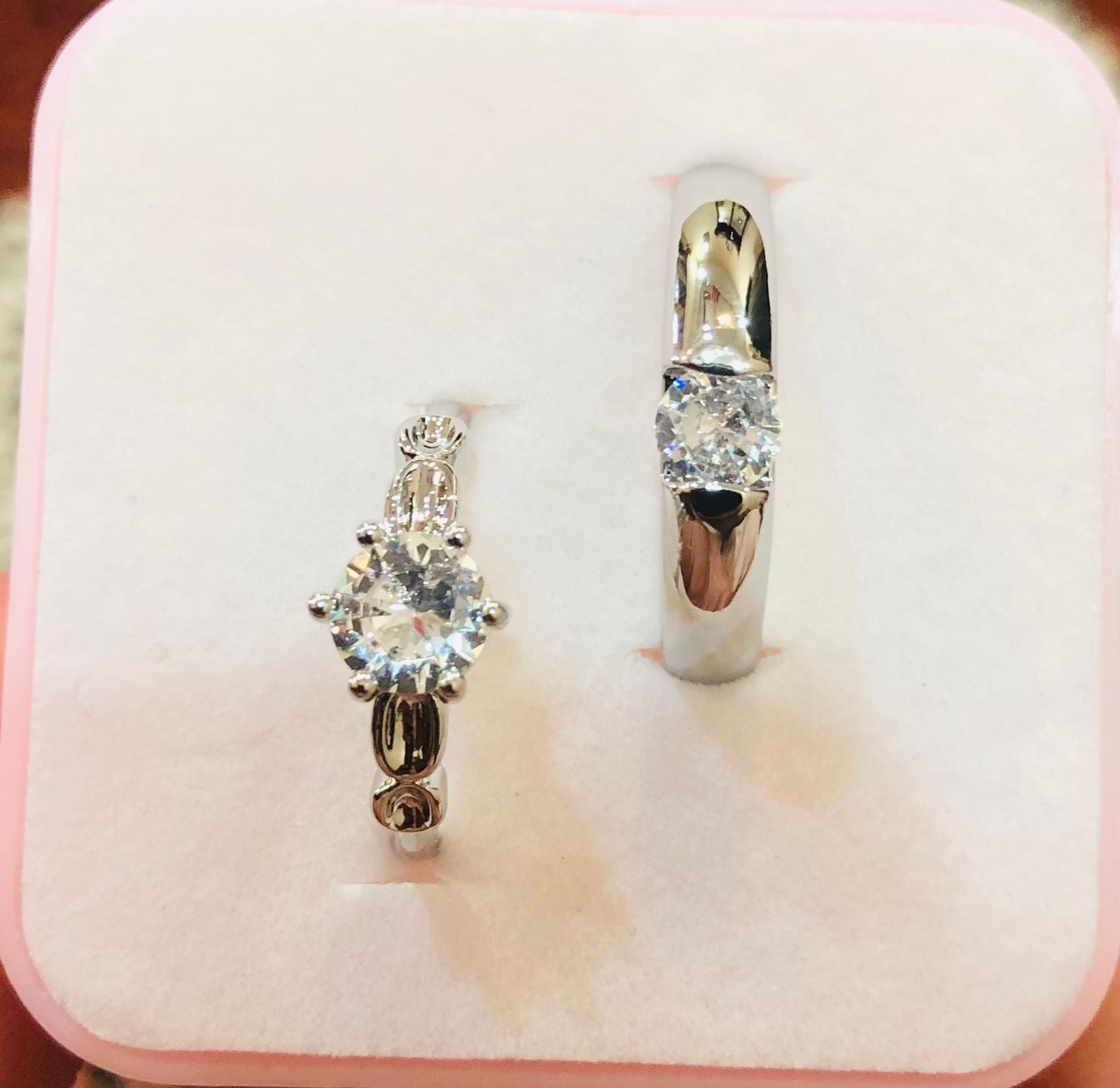 Two diamond rings on a pink jewelry box