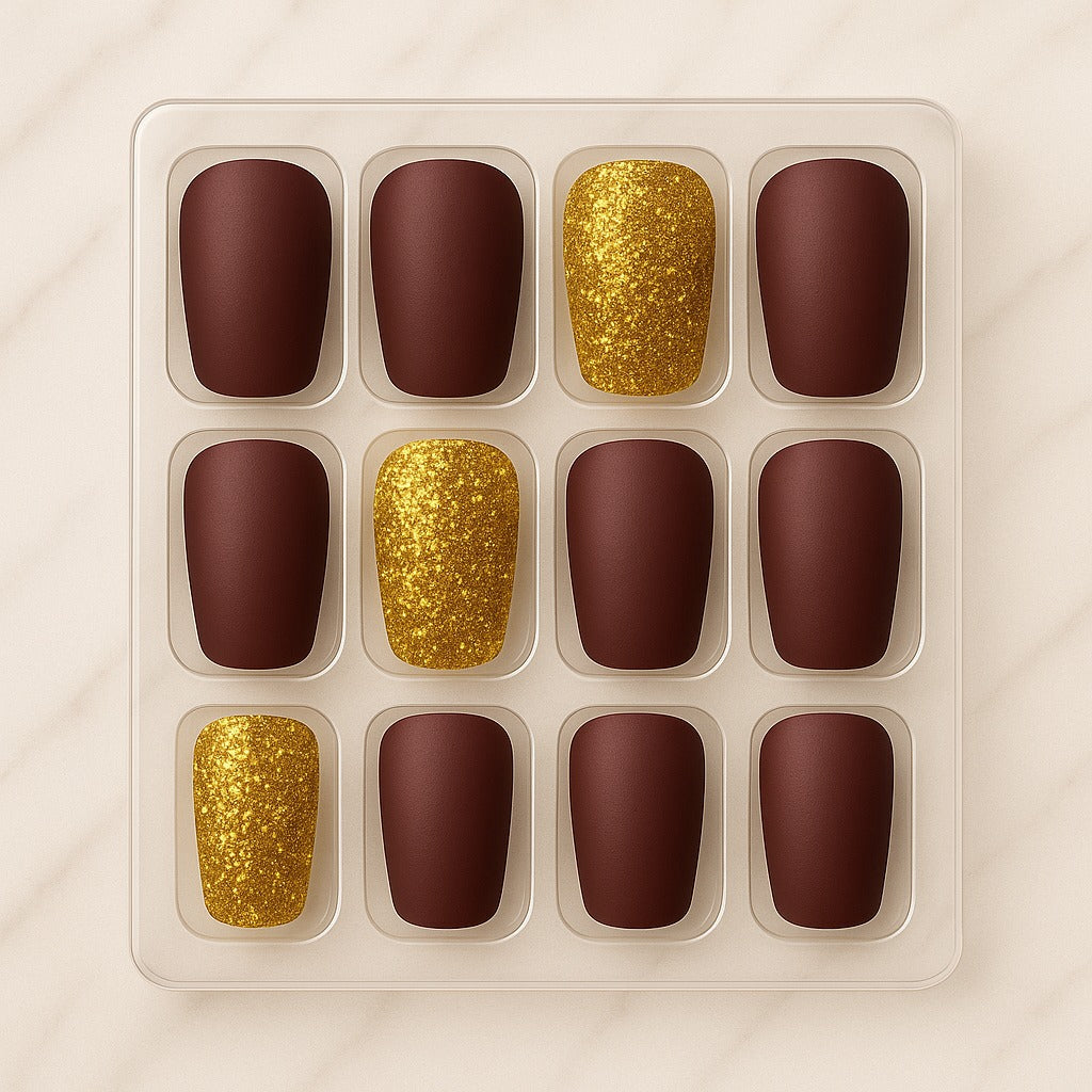 Set of nail designs with gold glitter and brown matte colors in a clear plastic tray.