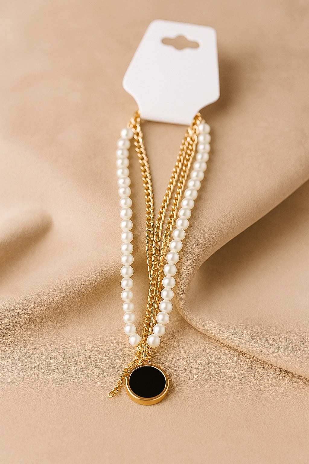 Layered necklace with white faux pearls, gold chain, and black round pendant