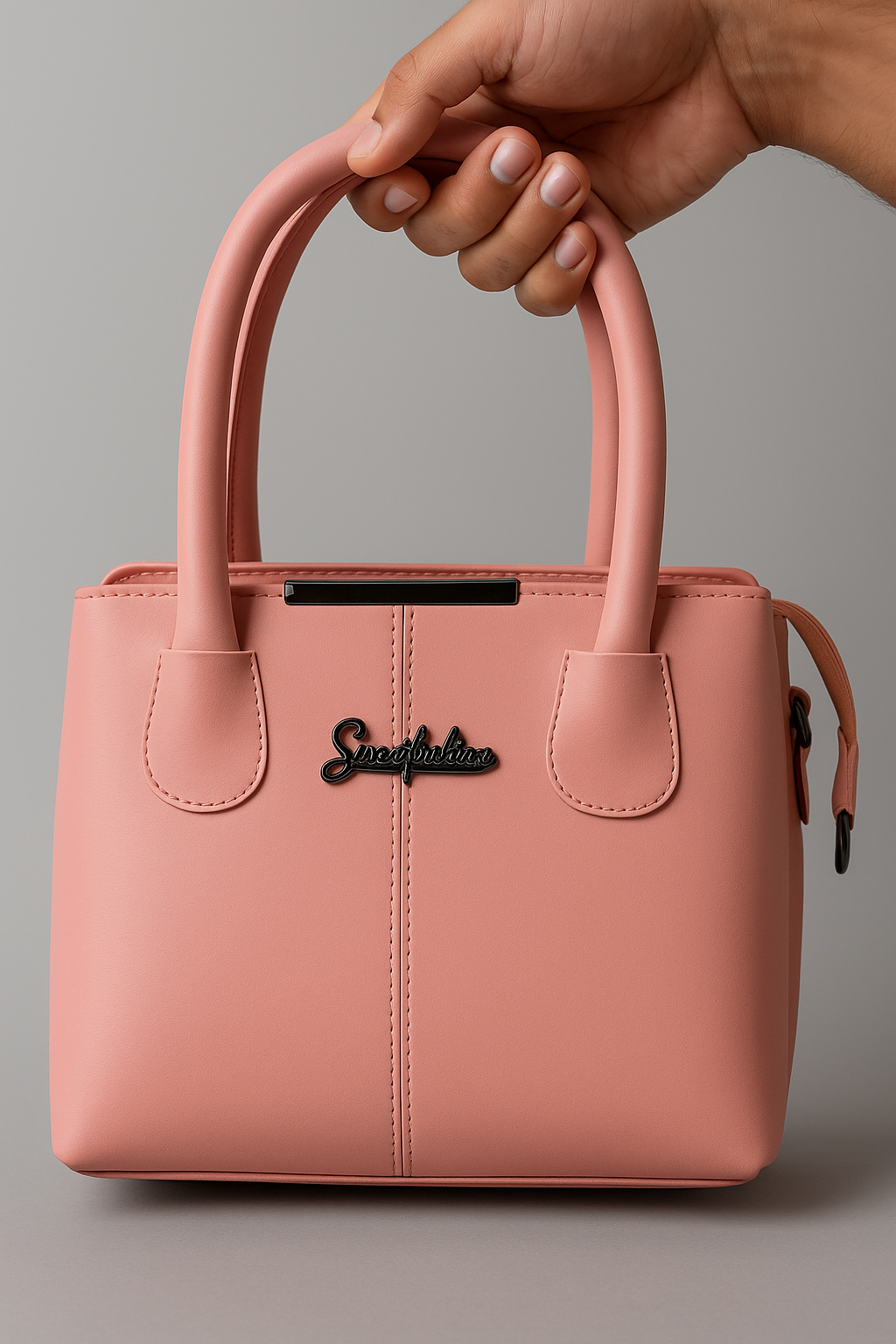 Pink handbag with 'Snoopy' branding held by a hand against a gray background
