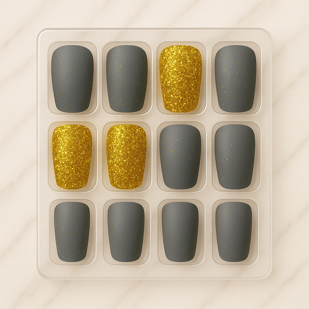 Set of nail designs with gold glitter and gray colors in a clear plastic tray.